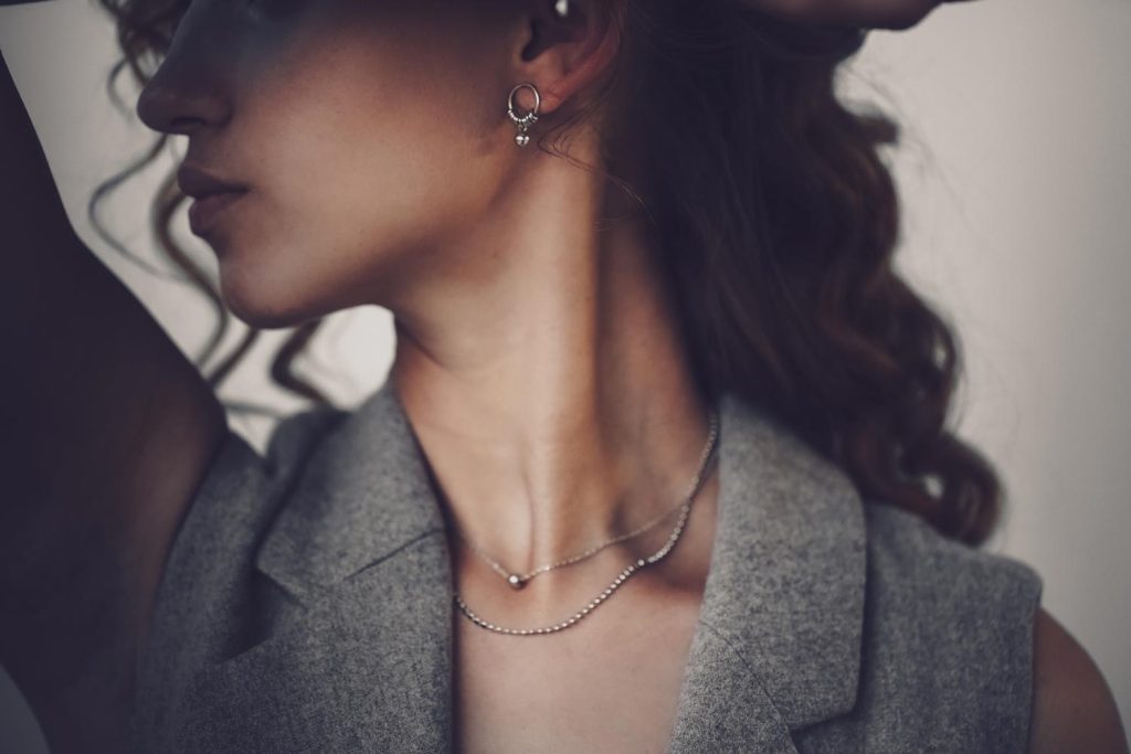 Model posiert mit Halsketten und Ohrring